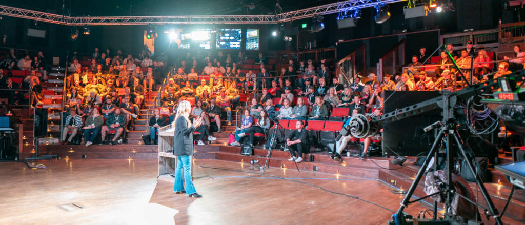 Conference speaker with attendees in the stand.